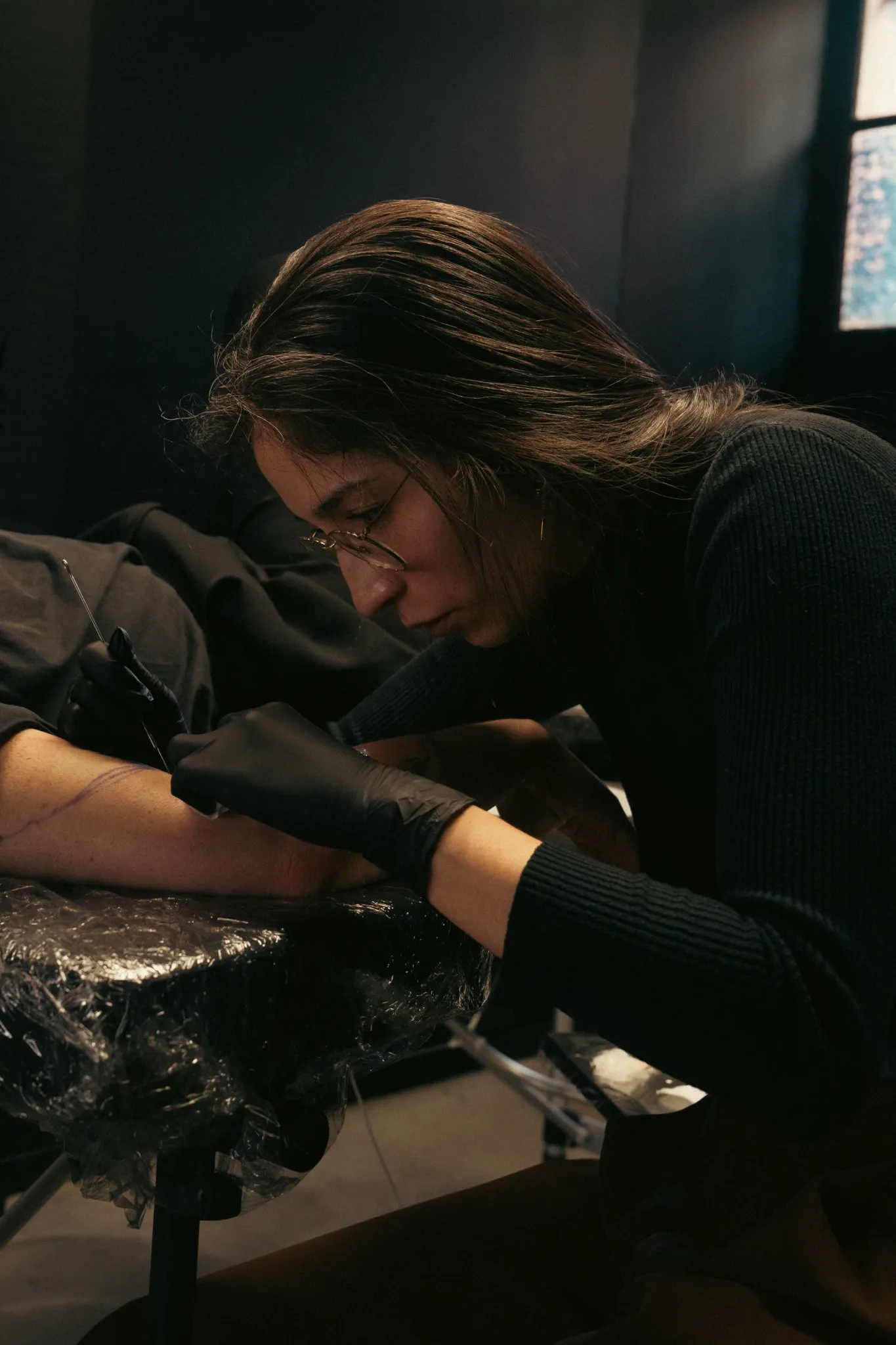 Geste précis d'une tatoueuse réalisant un handpoke à l'aiguille