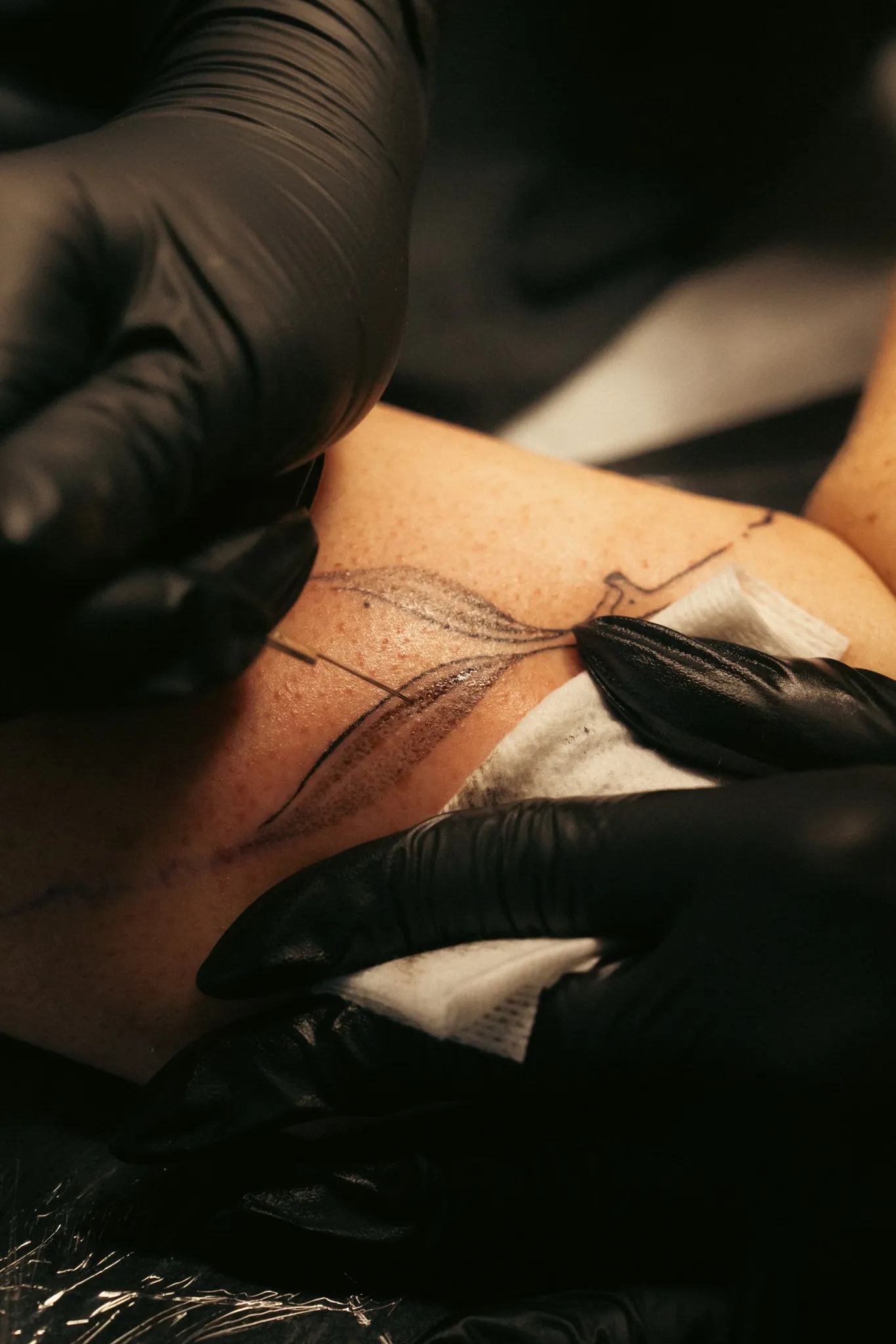 Motif végétal en ligne fine tatoué au handpoke, en cours de réalisation