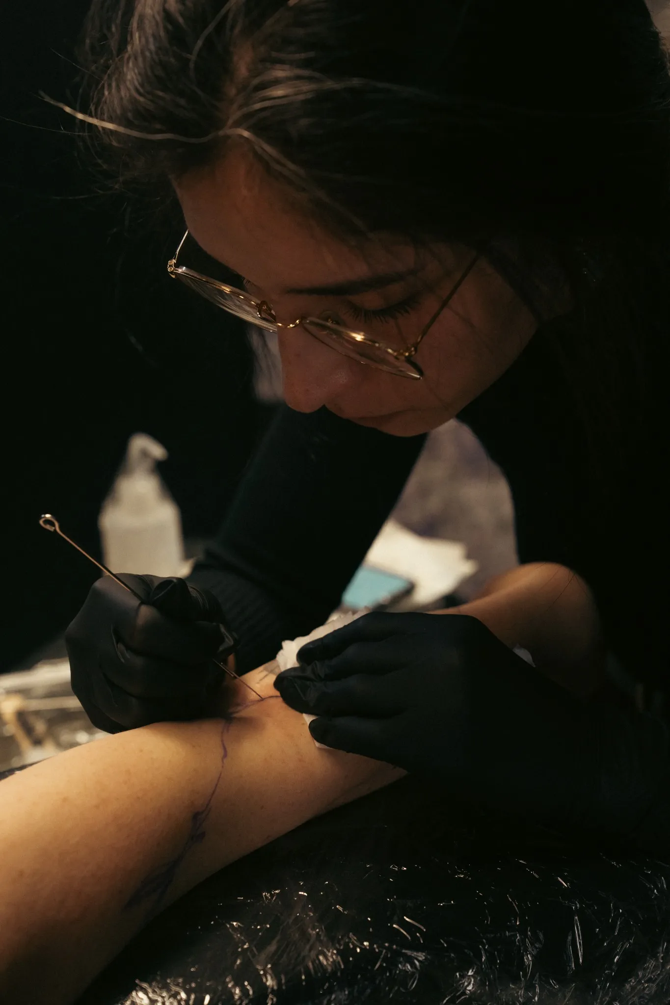 Marah, tatoueuse handpoke, concentrée pendant une séance de tatouage